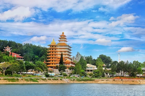 Ngôi Bảo tháp cao sừng sững, nổi bật giữa màu xanh của cây rừng, soi bóng xuống mặt hồ tĩnh lặng tại Núi Cấm